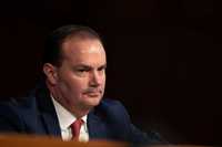 Mike Lee, a white ma n with short black hair and a blue suit, sitting at a congressional hearing.