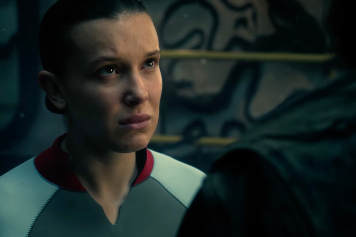 Millie Bobby Brown as Eleven in Stranger Things, wearing a grey swimsuit.