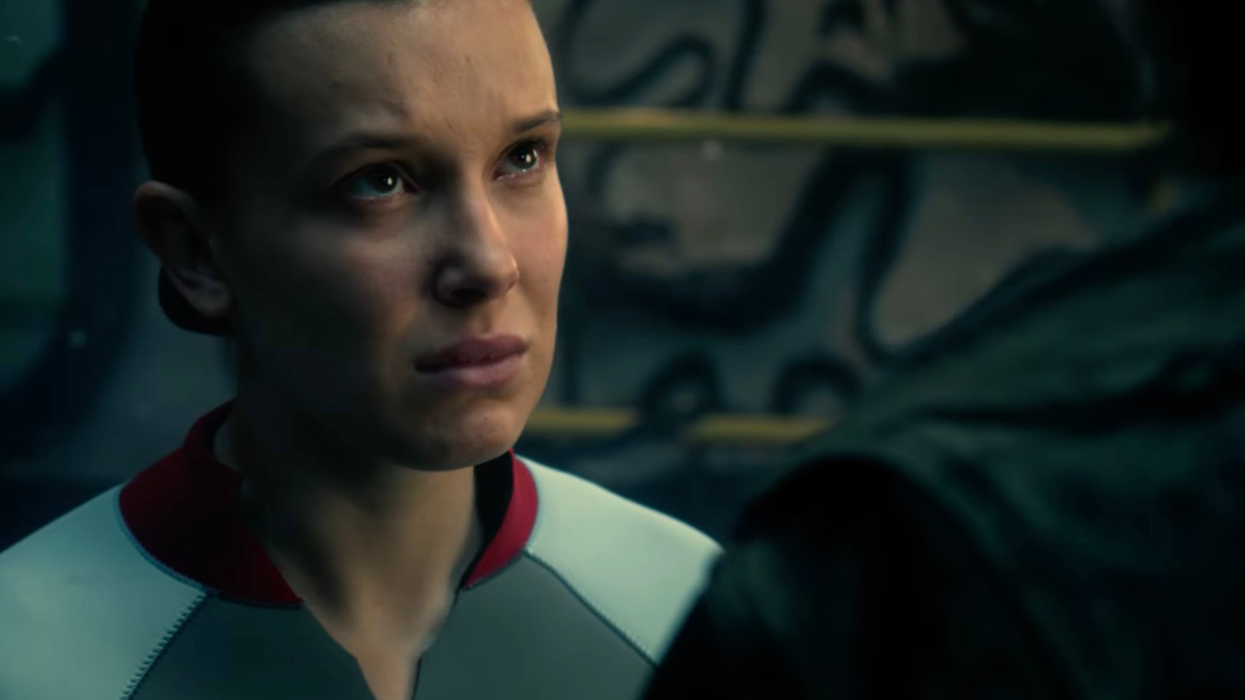 Millie Bobby Brown as Eleven in Stranger Things, wearing a grey swimsuit.