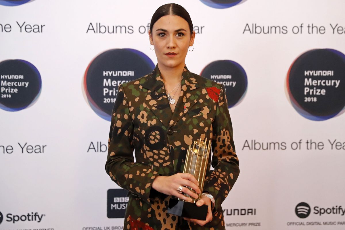 Nadine Shah holds the Mercury Prize for Album of the Year in front of a branded backdrop