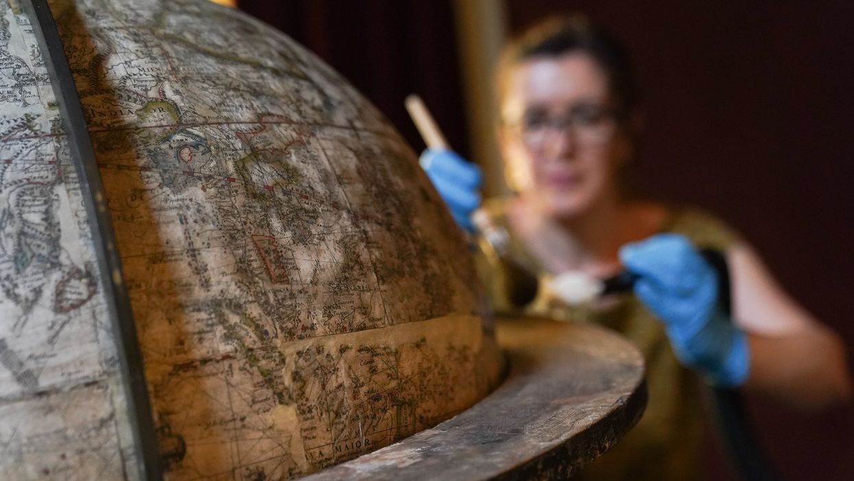 National Trust conservator Samantha Taylor cleans the rare Elizabethan globe (Andrew Matthews/PA)