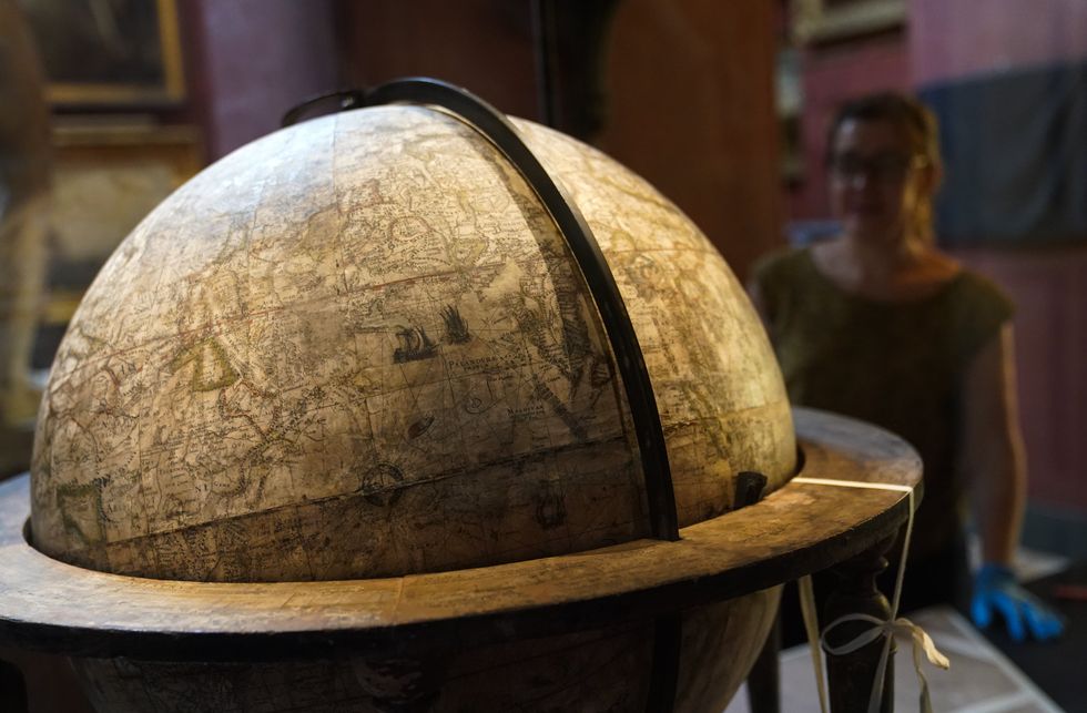 National Trust conservator Samantha Taylor inspects the rare Elizabethan globe (Andrew Matthews/PA)
