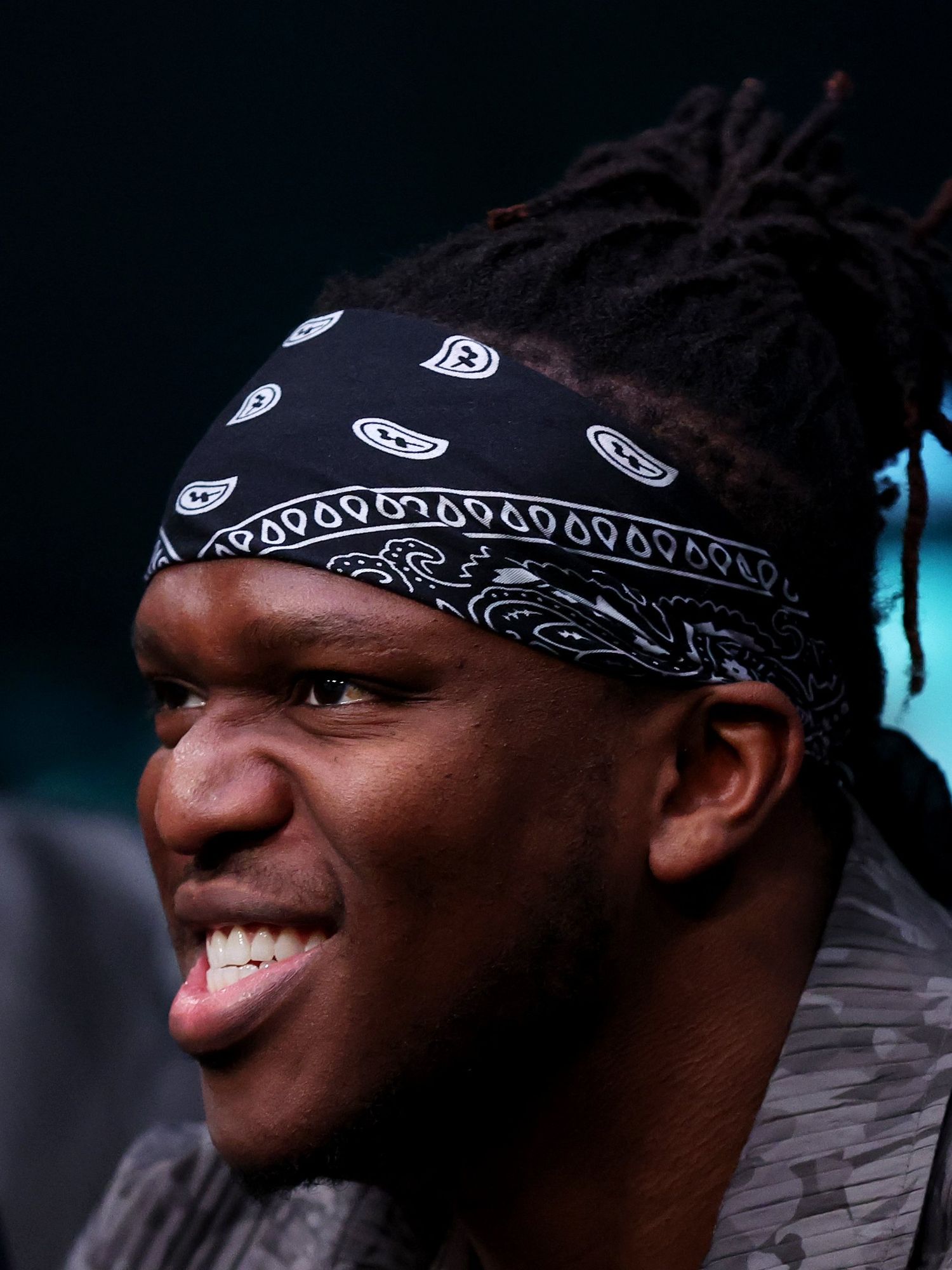 Olajide Olatunji, also known as KSI, grins while watching a boxing match.