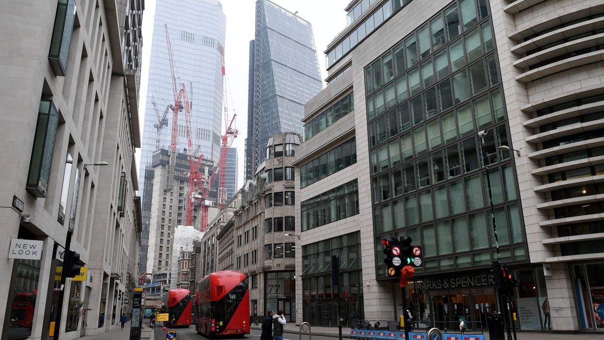 Pedestrians cross a near-deserted street in the City of London as the majority of offices remain closed