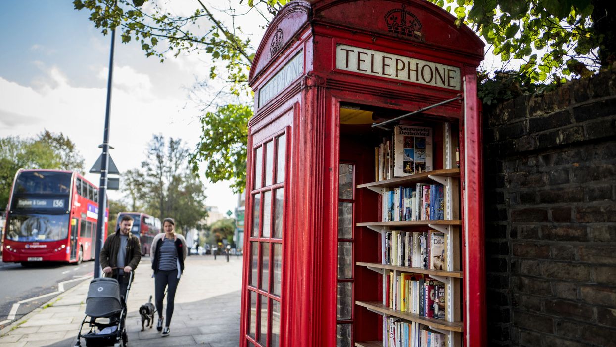 Pedestrians walk past a red telephone box turned into a book exchange library in south London.