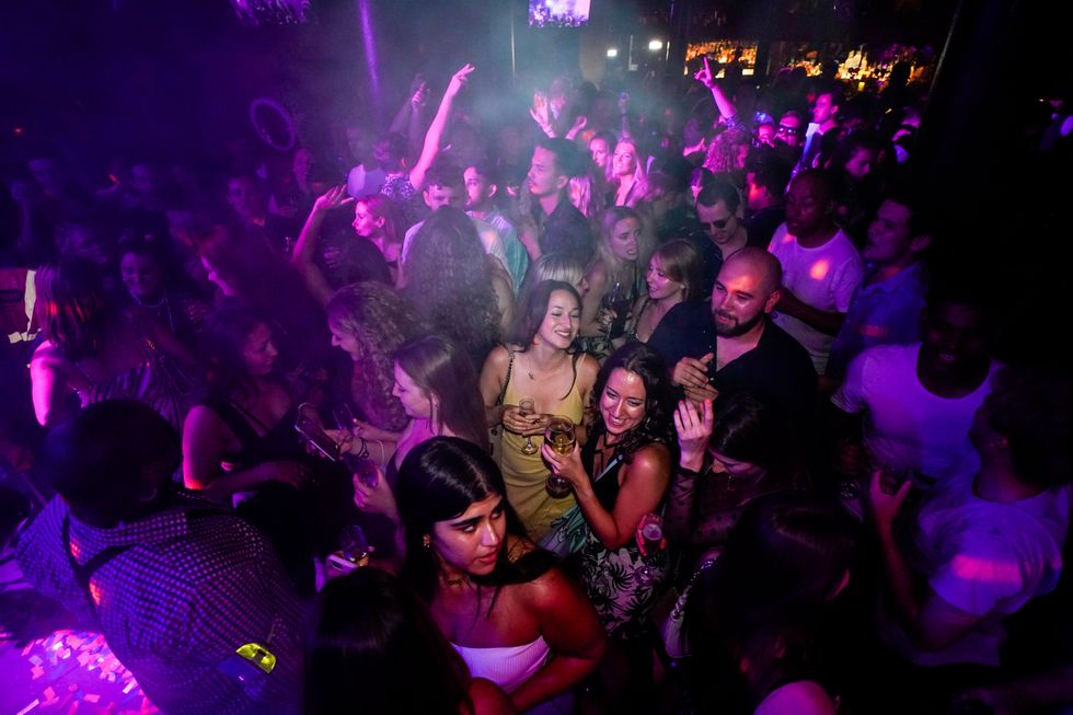 People drink on the dance floor shortly after the reopening, at The Piano Works in Farringdon, in London,