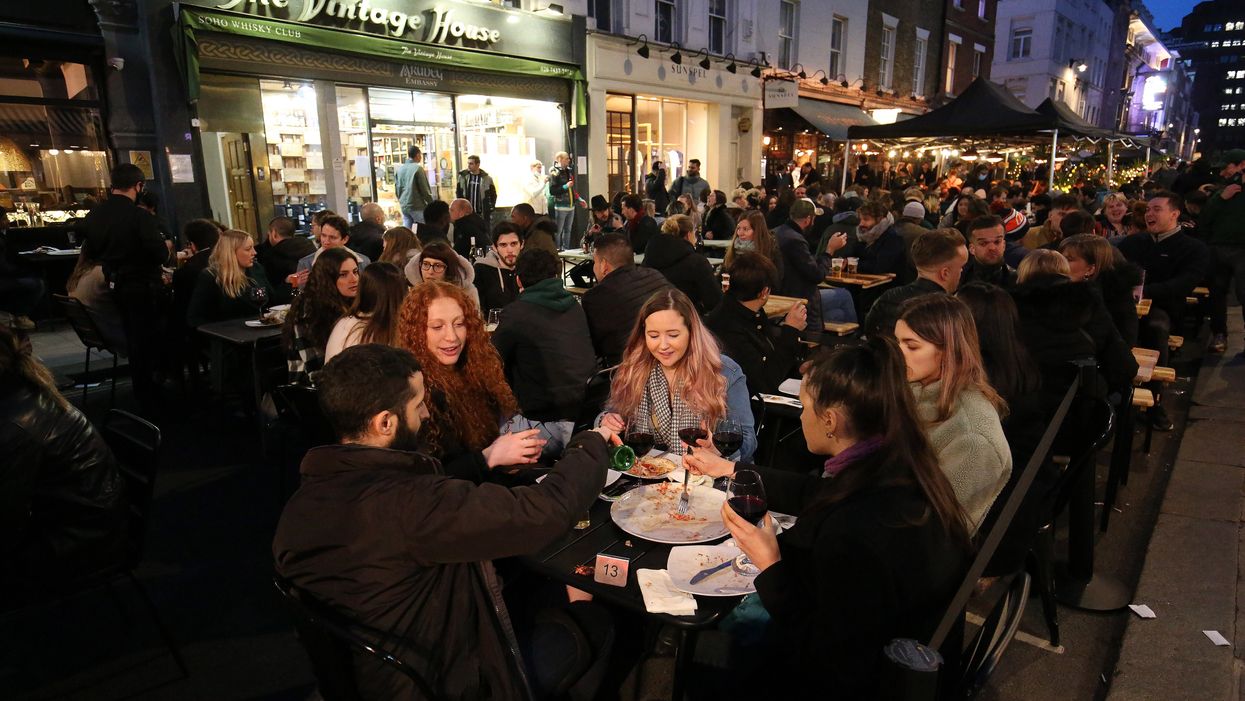 People eating and drinking outdoors in busy Soho street in London