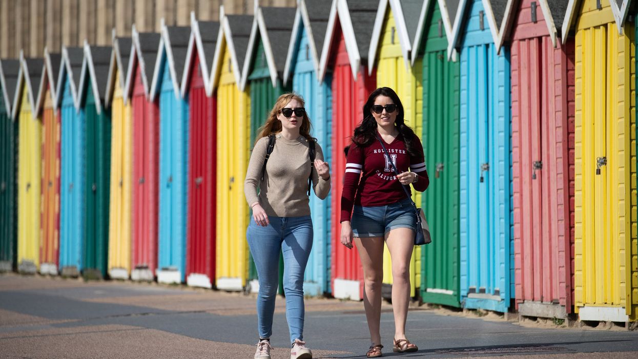 People make their way past beach huts on the sea front on Boscombe beach in Dorset