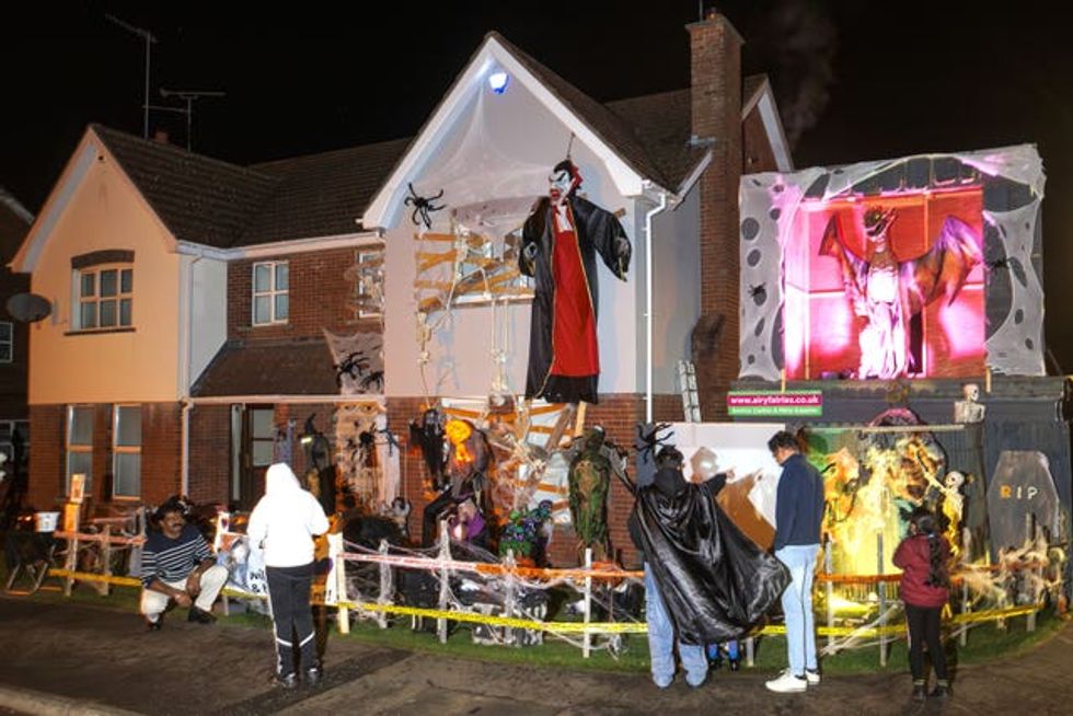 People pose and take pictures outside the Halloween display