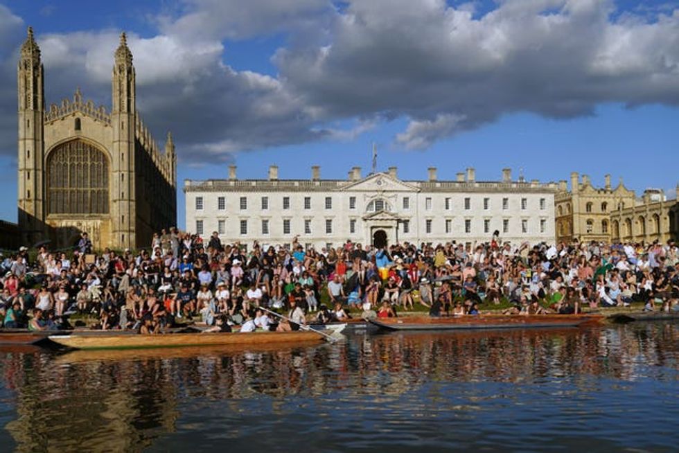 People sit on the banks of the River Cam, in punts on the water and on the lawns of King\u2019s College in Cambridge, as they listen to The King\u2019s Men perform