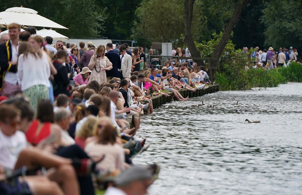 People sit on the banks of the river on the opening day of the 2021 Henley Royal Regatta alongside the river Thames (Andrew Matthews/PA)