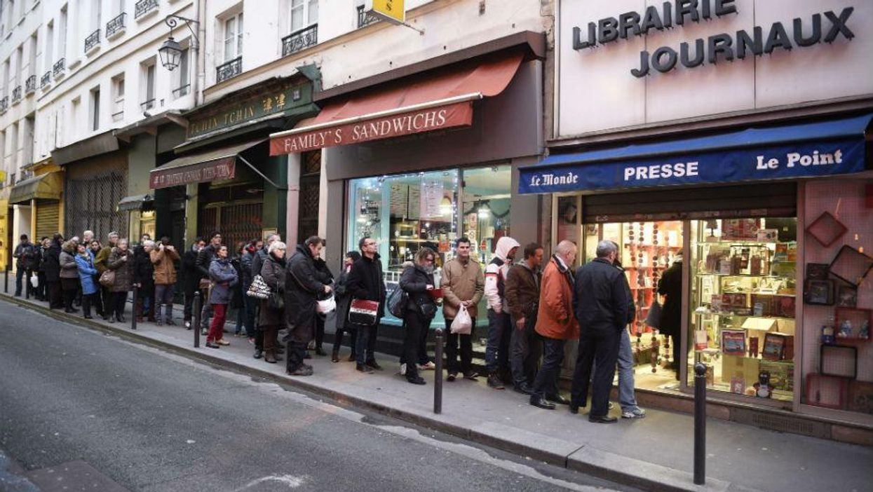 People wait outside a newsagents in Paris on Wednesday morning