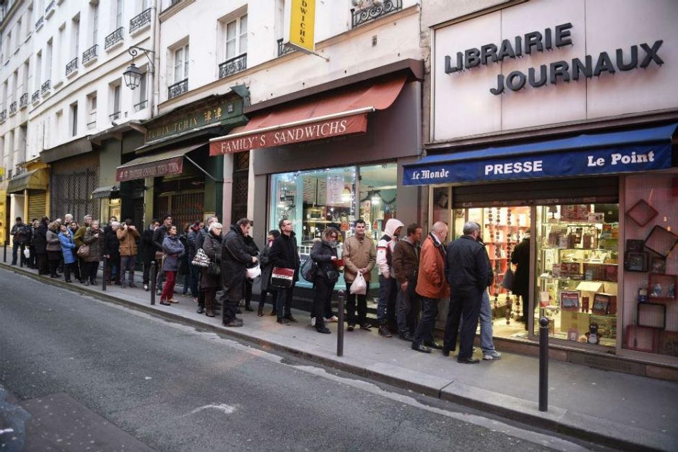 People wait outside a newsagents in Paris on Wednesday morning
