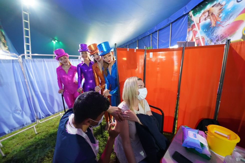 Performers from Circus Extreme watch as Rhiannon Alexander, 34, from Bradford, receives a Covid-19 vaccination at a pop-up clinic in a marquee in Halifax (Owen Humphreys/PA)