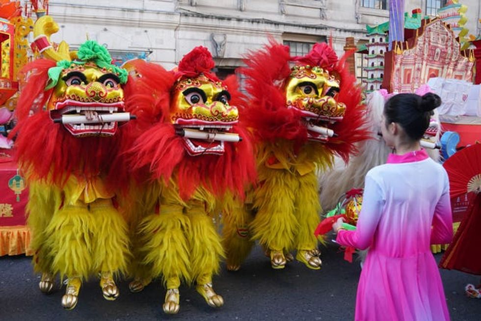 Performers in gold outfits with scrolls in their mouth ahead of the lunar new year celebrations