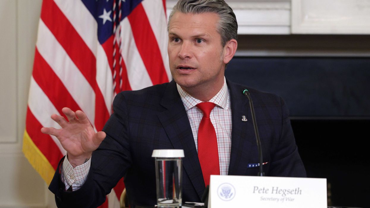 Pete Hegseth, a white man with short grey hair, a black suit and a red tie, talking from beind a desk.