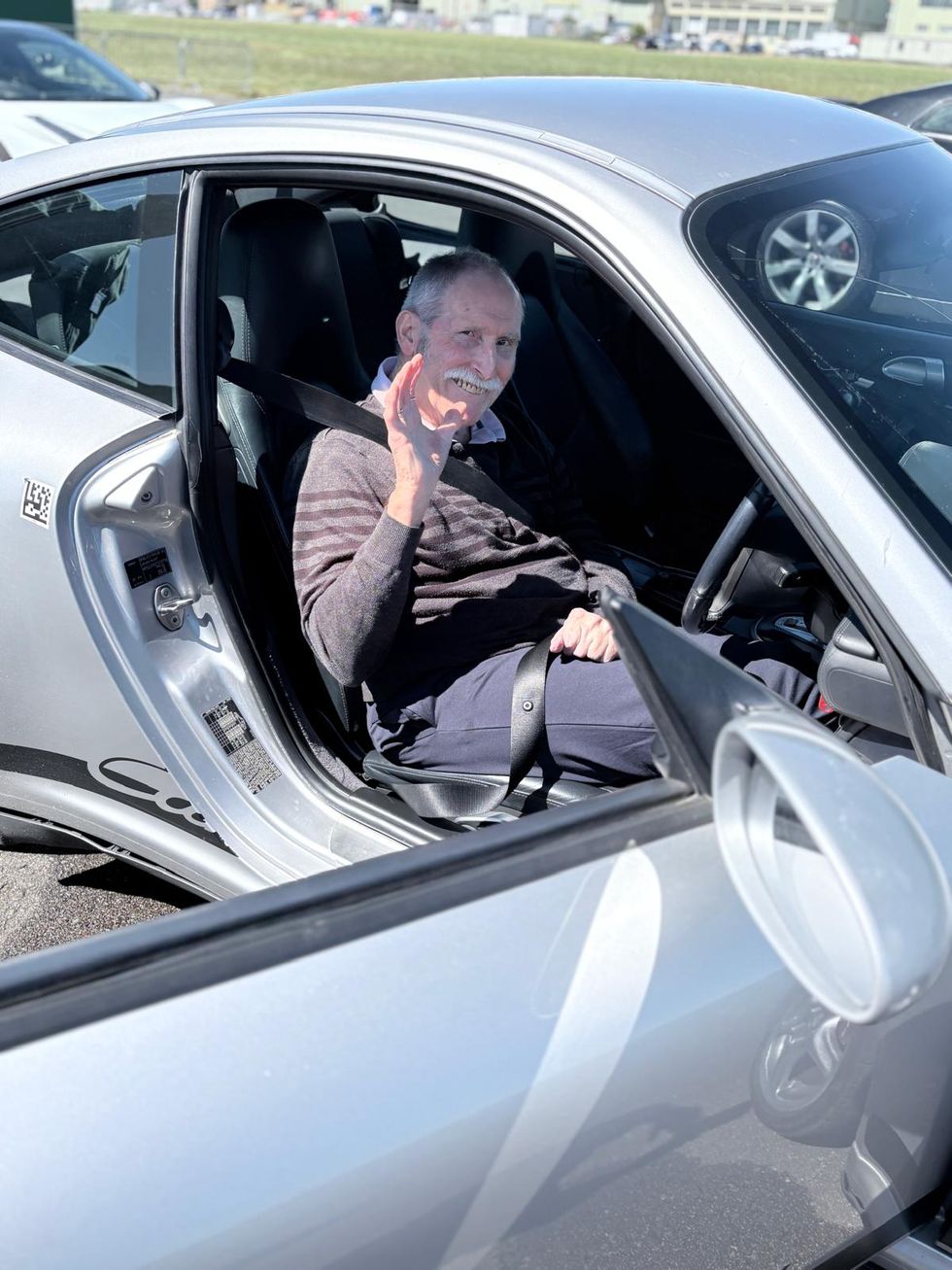 Peter Kluss, 74, sitting in a supercar and waving at the camera