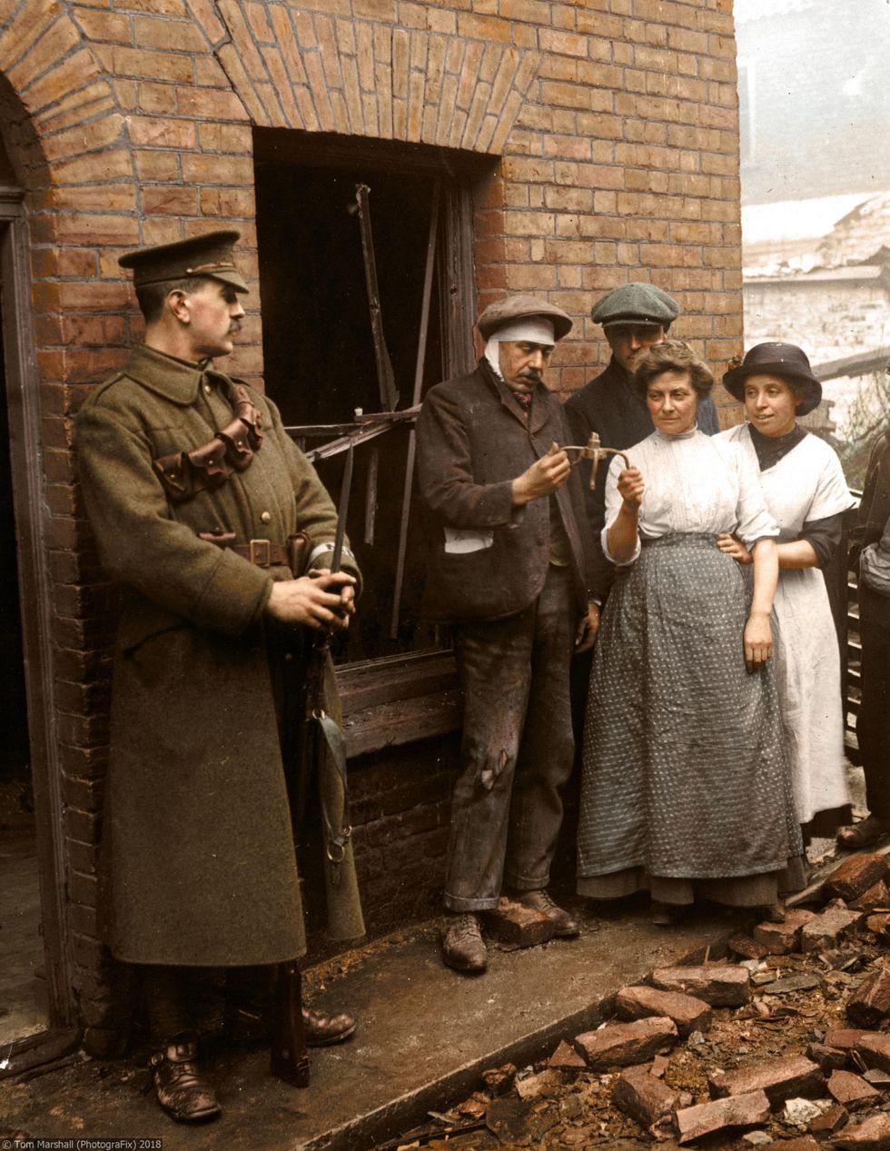 Picture: A family are pictured holding a fragment of a bomb after a zeppelin raid, surrounded by bricks and wreckage left by the raid