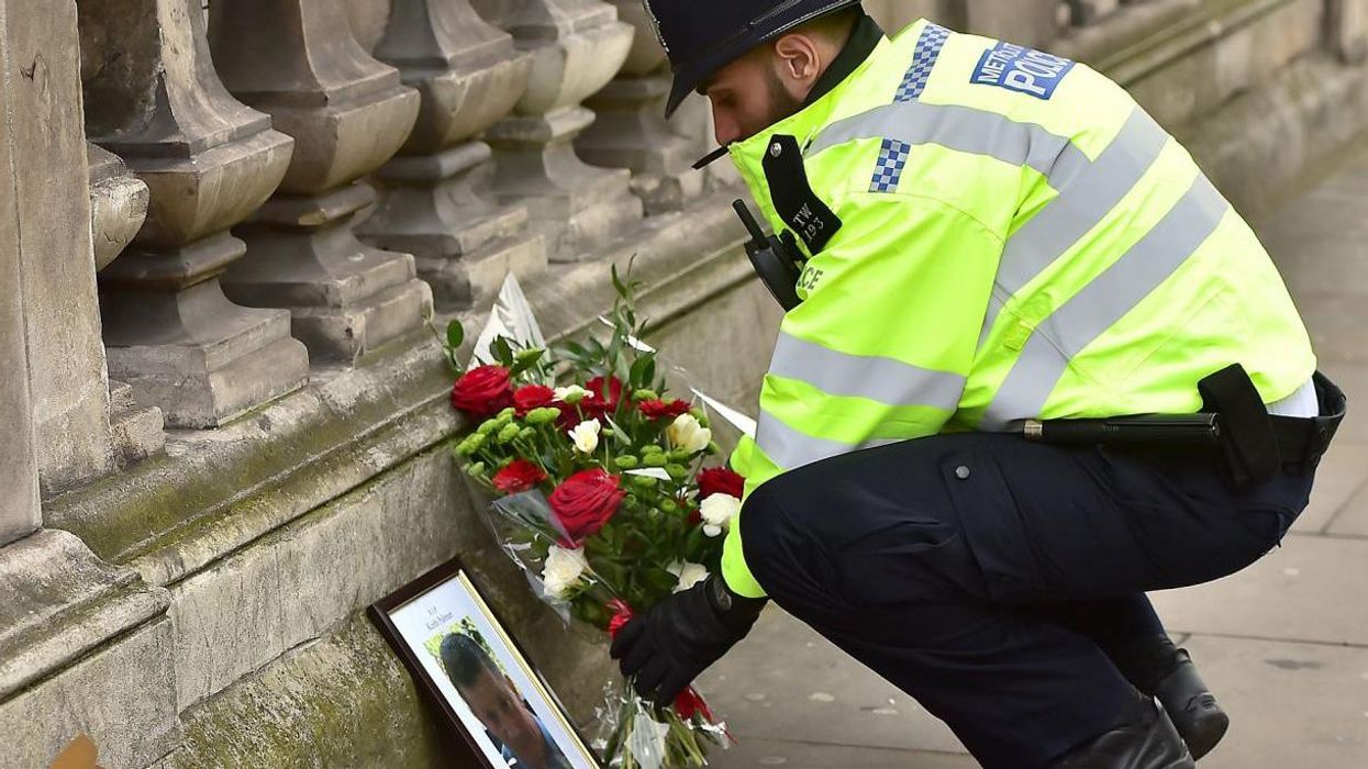 Picture: A police officer places flowers and a photo of PC Keith Palmer on Whitehall near the Houses of Parliament
