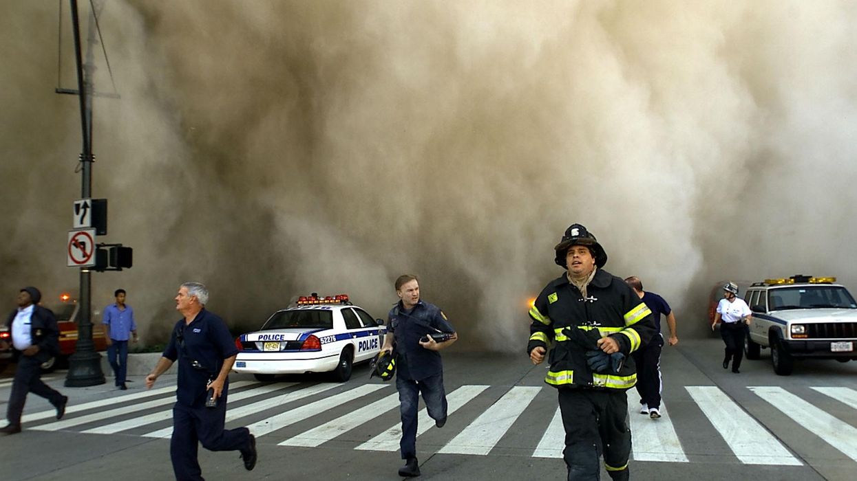 Policemen and firemen run away from the huge dust cloud caused as the World Trade Center's Tower One collapses after terrorists crashed two hijacked planes into the twin towers, 11 September, 2001 in New York City. Picture: