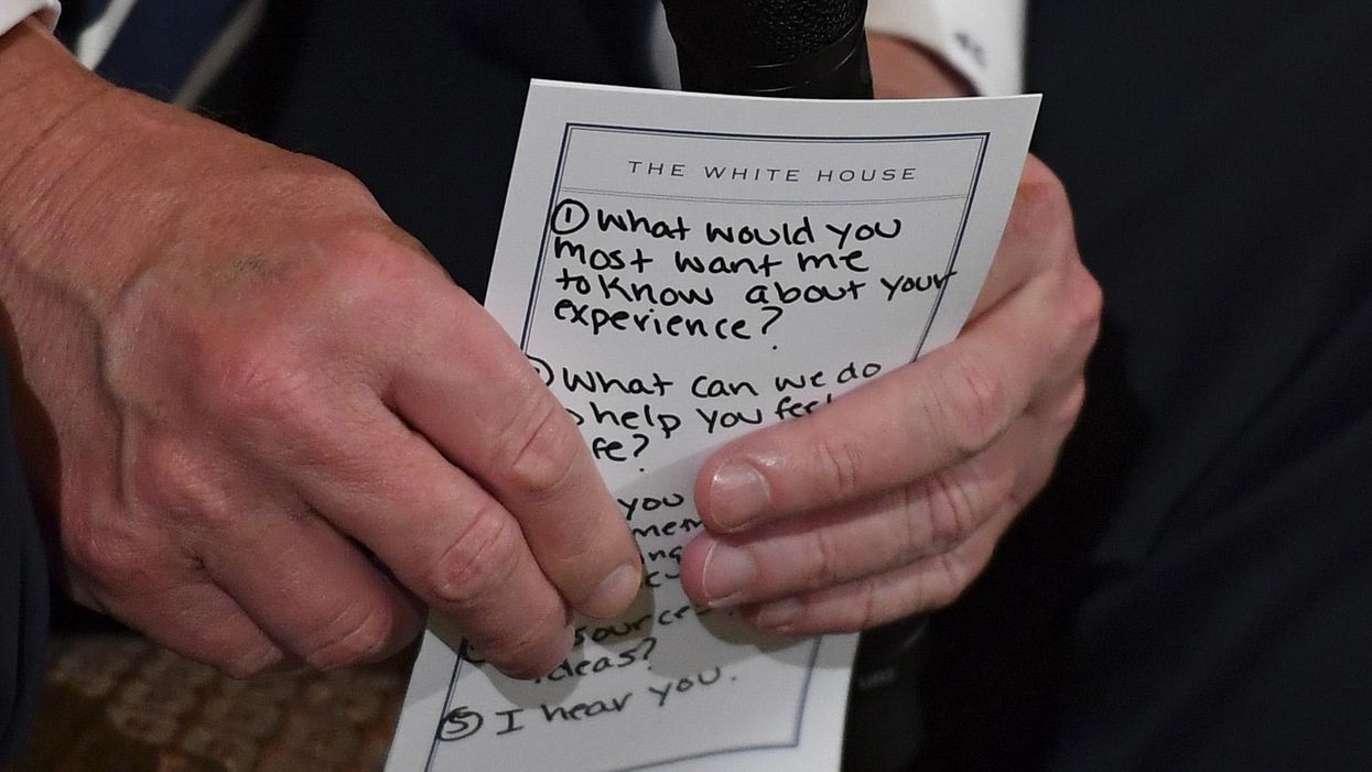 President Donald Trump holds a card with questions during a listening session with high school students and teachers in the State Dining Room at the White House on Wednesday