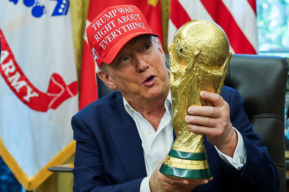 President Donald Trump wears a 'Trump Was Right About Everything!' hat while holding the FIFA World Cup Trophy, as he makes an announcement on the 2026 FIFA World Cup, in the Oval Office at the White House in Washington, D.C., U.S., August 22, 2025
