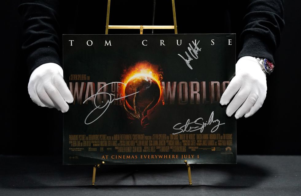 Prop Store poster consultant Mark Hochman holds a Tom Cruise, Steven Spielberg and Justin Chatwin autographed cinema poster for the 2005 film War Of The Worlds (Andrew Matthews/PA)