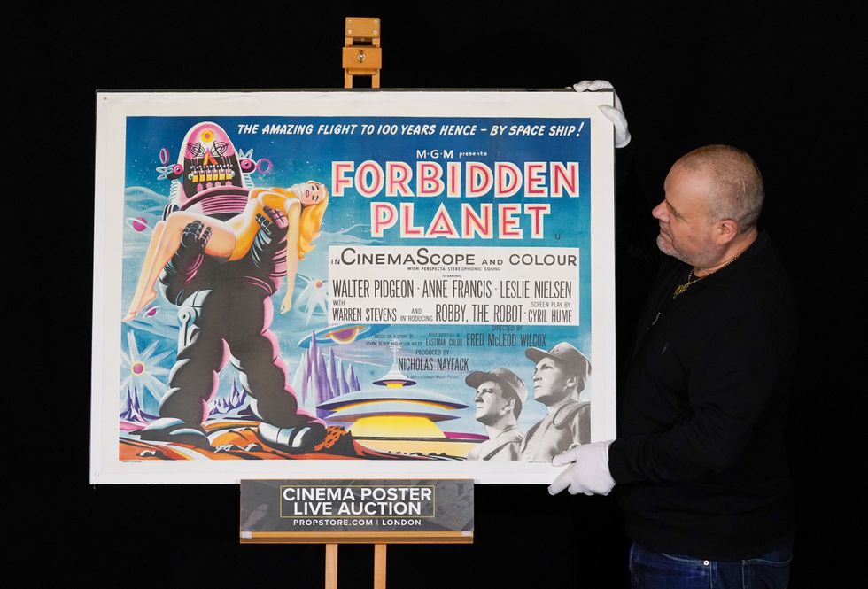 Prop Store poster consultant Mark Hochman looks at a UK Quad poster from the 1956 film Forbidden Planet (Andrew Matthwes/PA)