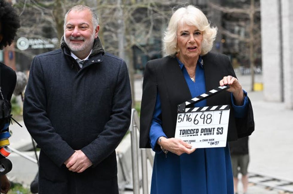 Queen Camilla operates the clapperboard with executive producer Jed Mercurio during a visit to the set of ITV drama Trigger Point in north London