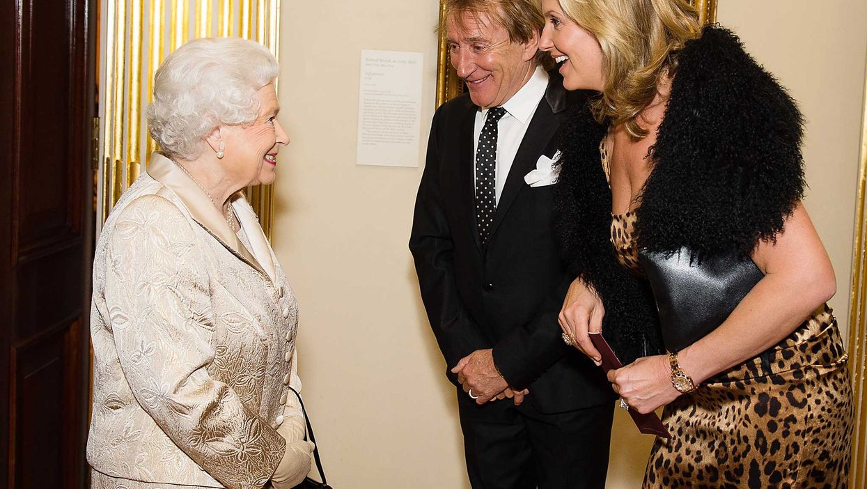 Queen Elizabeth II greets Sir Rod Stewart and wife Penny Lancaster after he was awarded a knighthood in recognition of his services to music and charity earlier in the day as they attend a reception and awards ceremony at Royal Academy of Arts