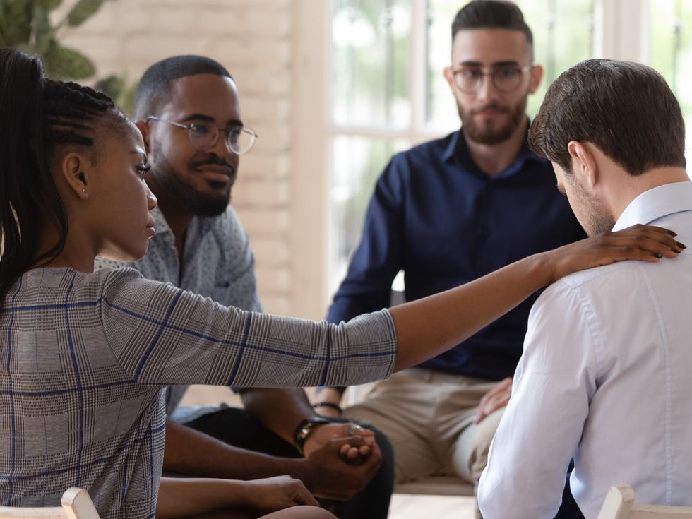 Rear view at upset man feel pain depression problem addiction get psychological support of counselor therapist coach diverse people friend group help patient during therapy counseling session concept