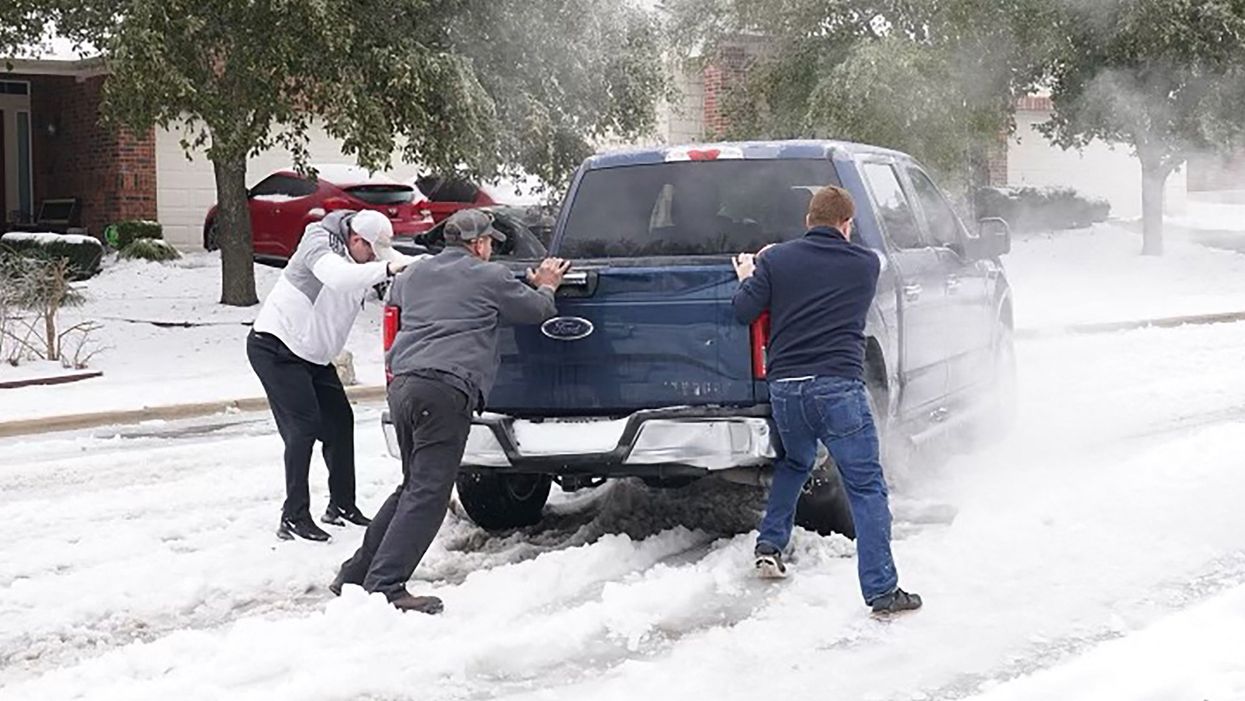 Residents help a pickup driver get out of ice on the road in Round Rock, Texas, on 17 February, 2021, after a winter storm