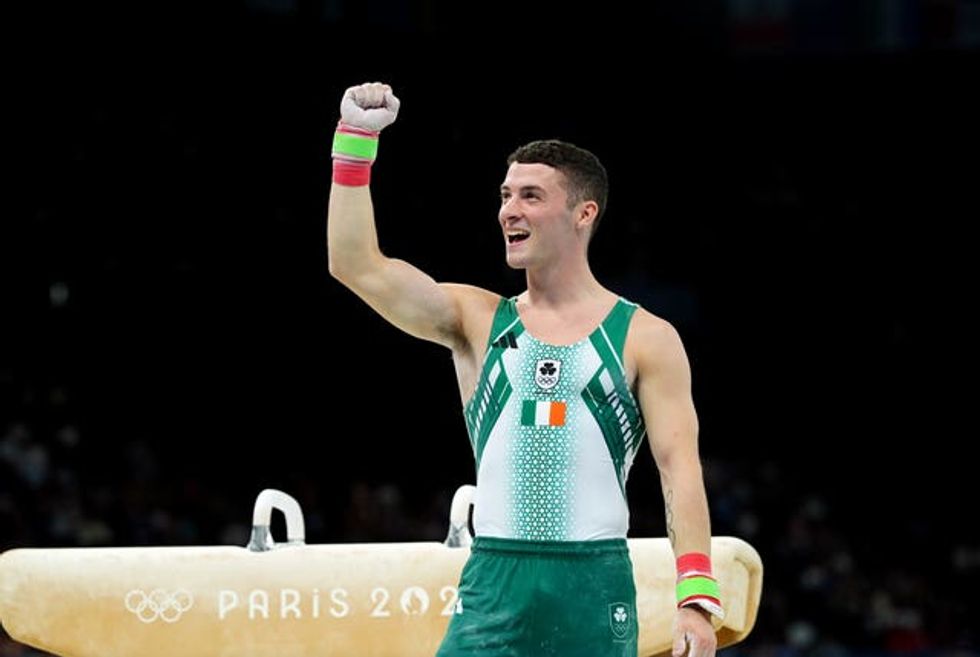 Rhys McClenaghan raises his arm in front of a pommel horse