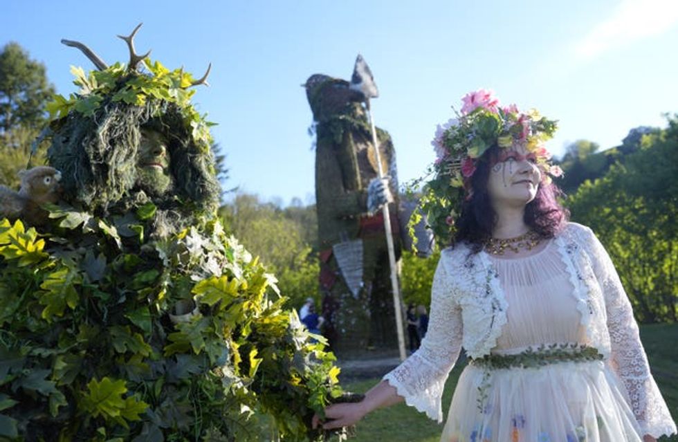 Richard and Jenni Thompson, depicting the Green Man and May Queen, in front of a giant wicker man