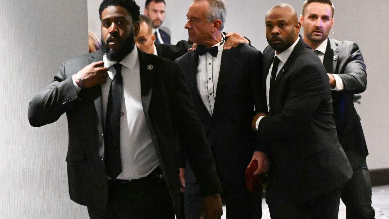 Robert F Kennedy Jr is escorted from the White House Correspondents' Dinner by federal agents in suits.