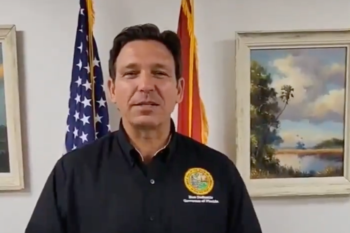 Ron DeSantis wearing a black shirt speaks directly to the camera in a smartphone video.
