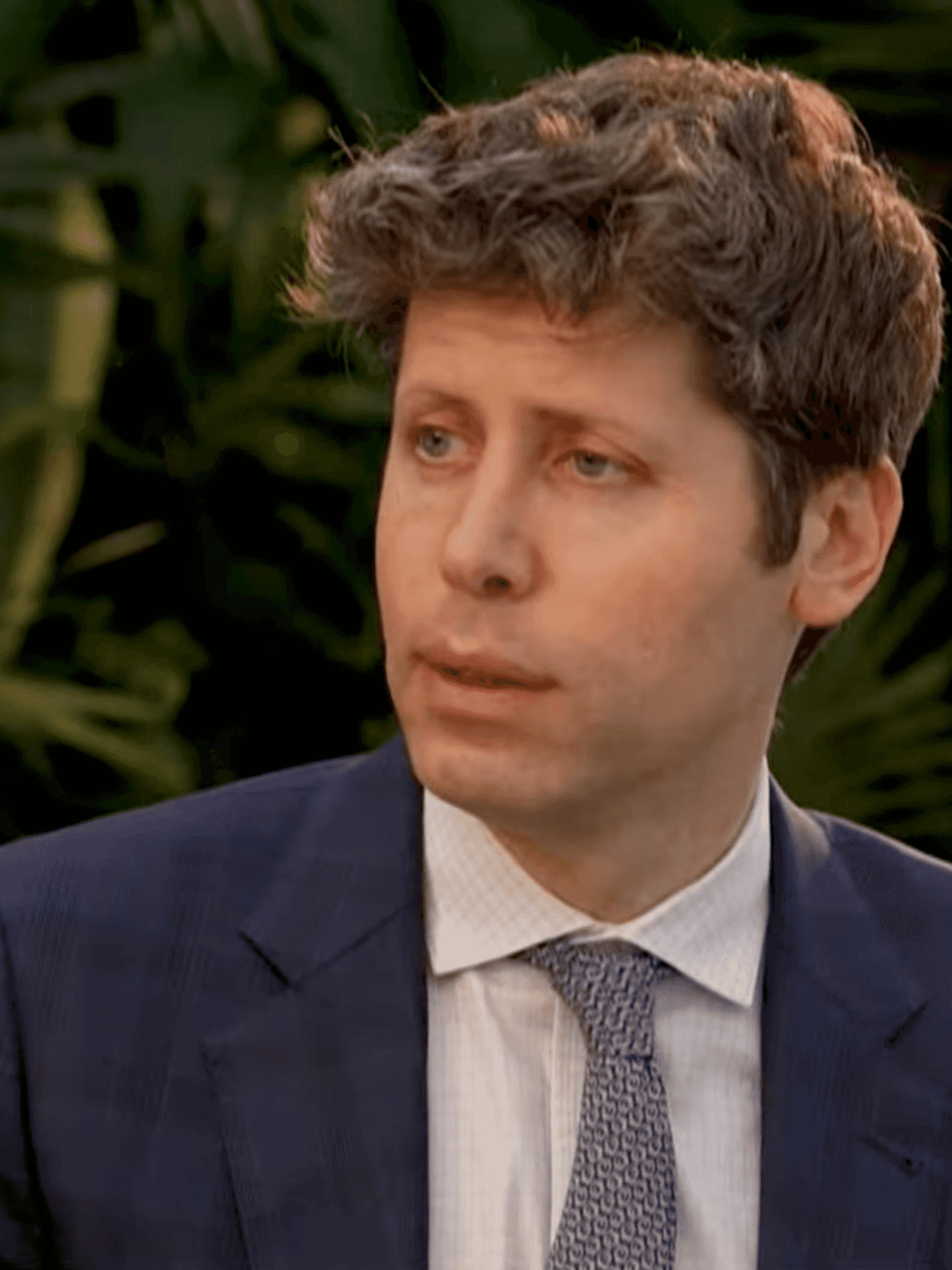 Sam Altman, a white man with short curly brown hair and a blue suit and tie.