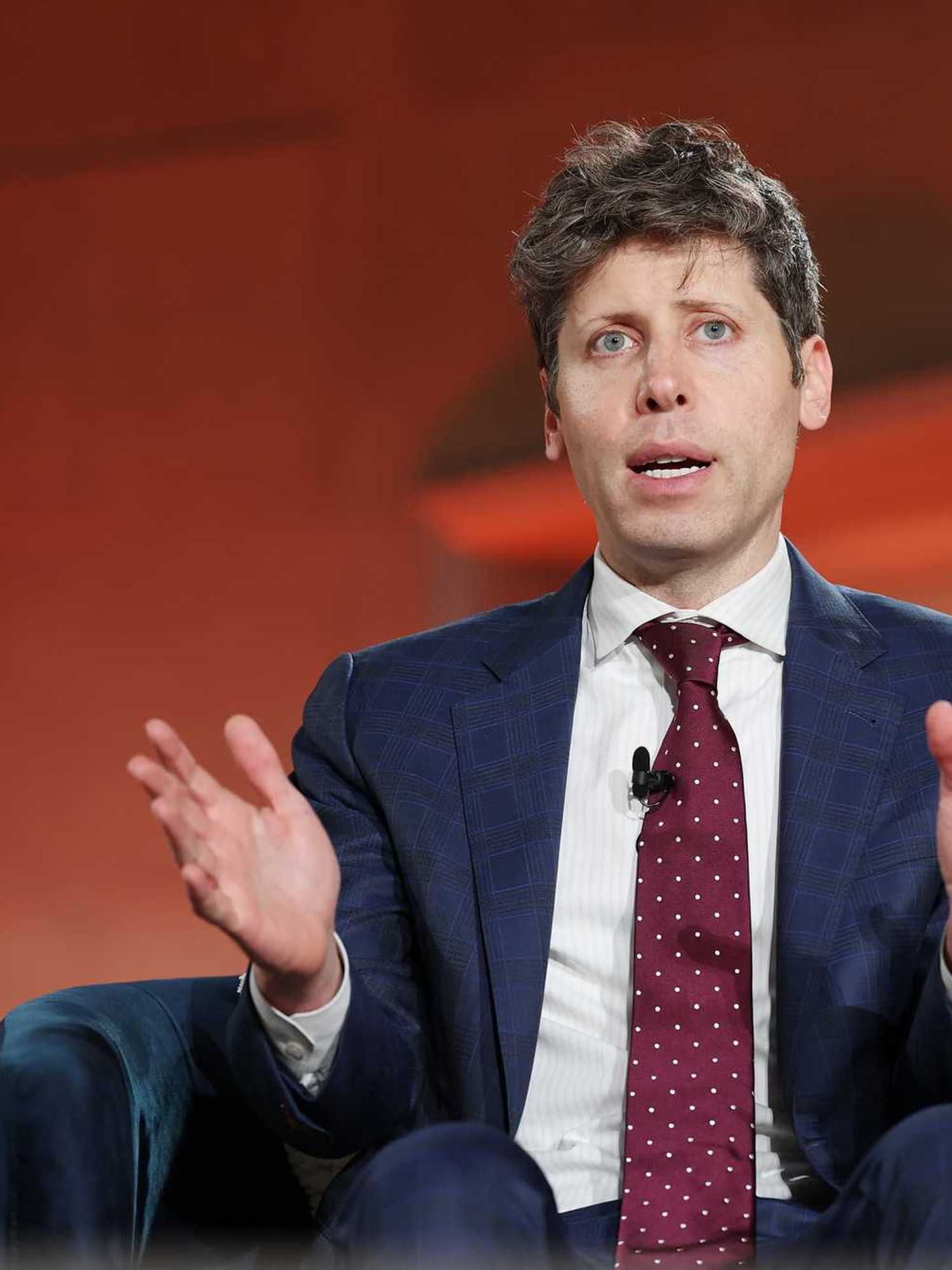 Sam Altman sitting on a black chair and speaking at the BlackRock US Infrastructure Summit.
