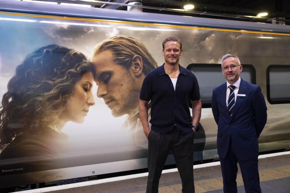 Sam Heughan with Graham Kelly in front of the Outlander-wrapped train