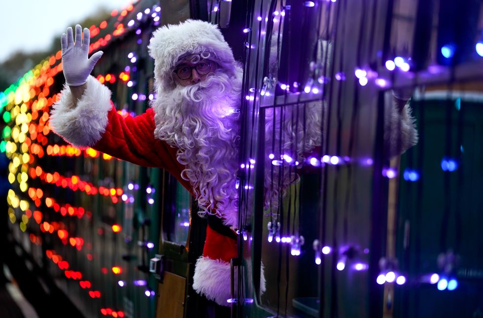 <p>Santa Claus waves as he leans out of a carriage (Andrew Matthews/PA)</p>