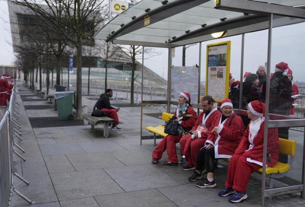 Santas enjoy a seat on a public transport bench