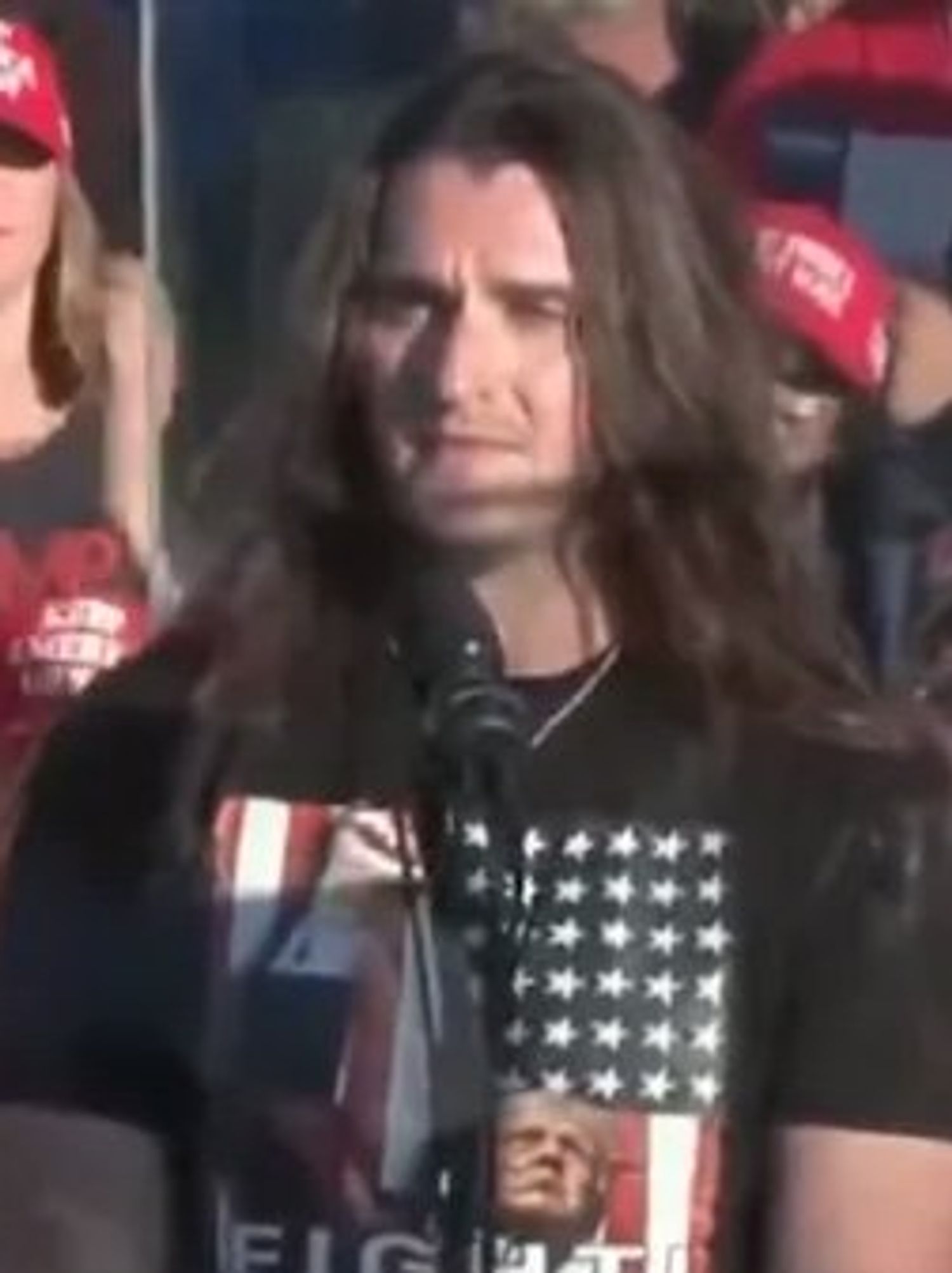 Scott Presler, a white man with long brown hair and a black t-shirt, addresses a Trump rally in Butler, Pennsylvania