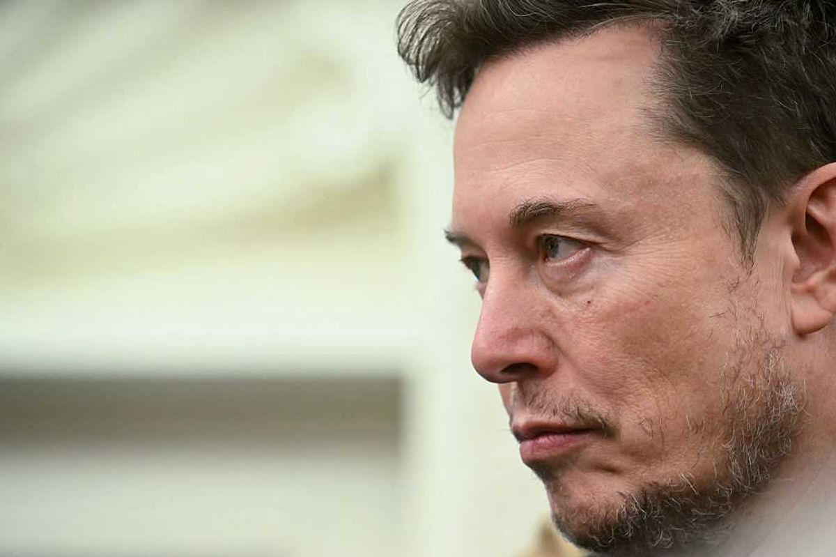 Side profile of Elon Musk, a bearded white man with short black hair and a neutral facial expression.