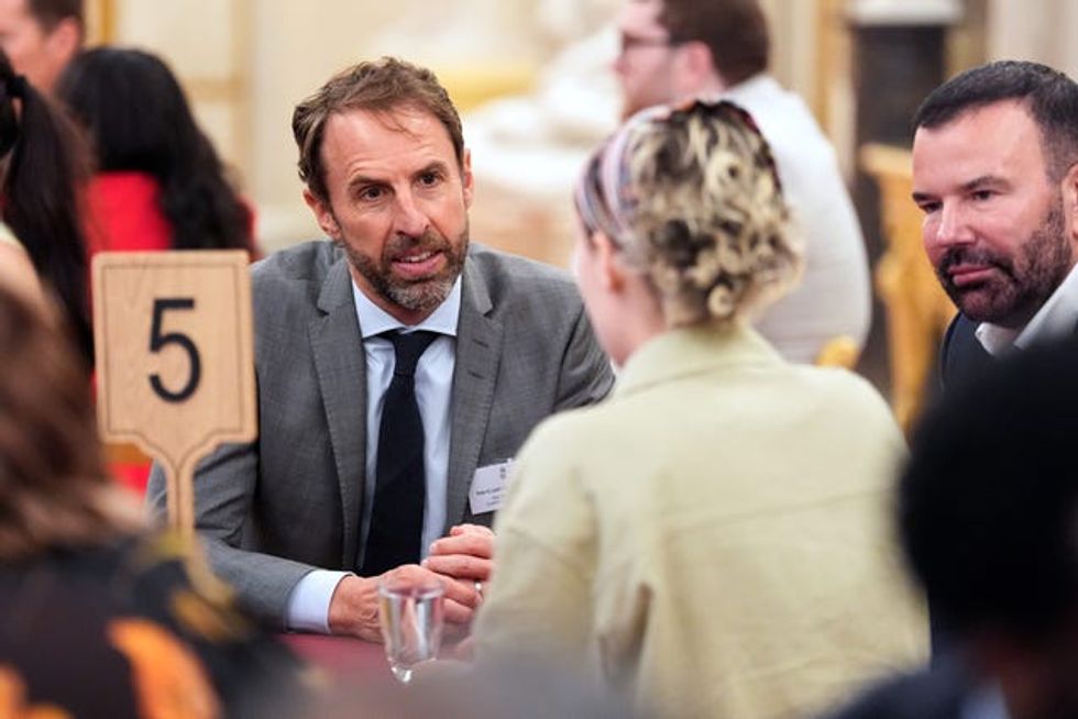 Sir Gareth Southgate speaking to a woman, who has her back to camera, at a table