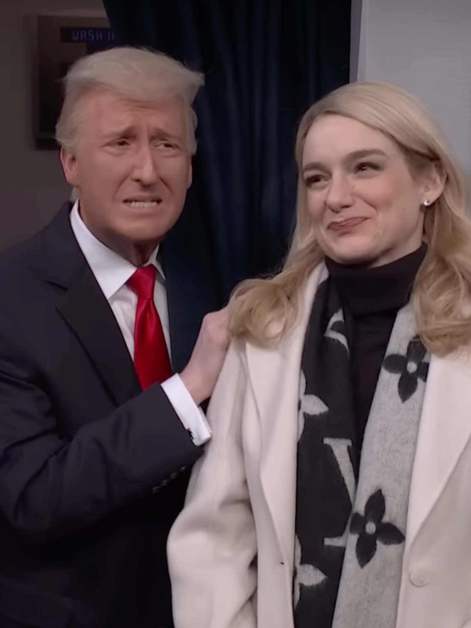 SNL skit. James Austin Johnson as Donald Trump and Ashley Padilla as Karoline Leavitt. Johnson is placing a hand on Leavitt's shoulder, who is smiling warmly.