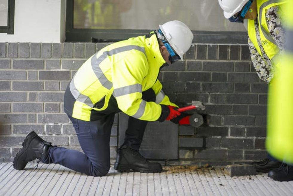 Someone in hi-vis chisels bricks