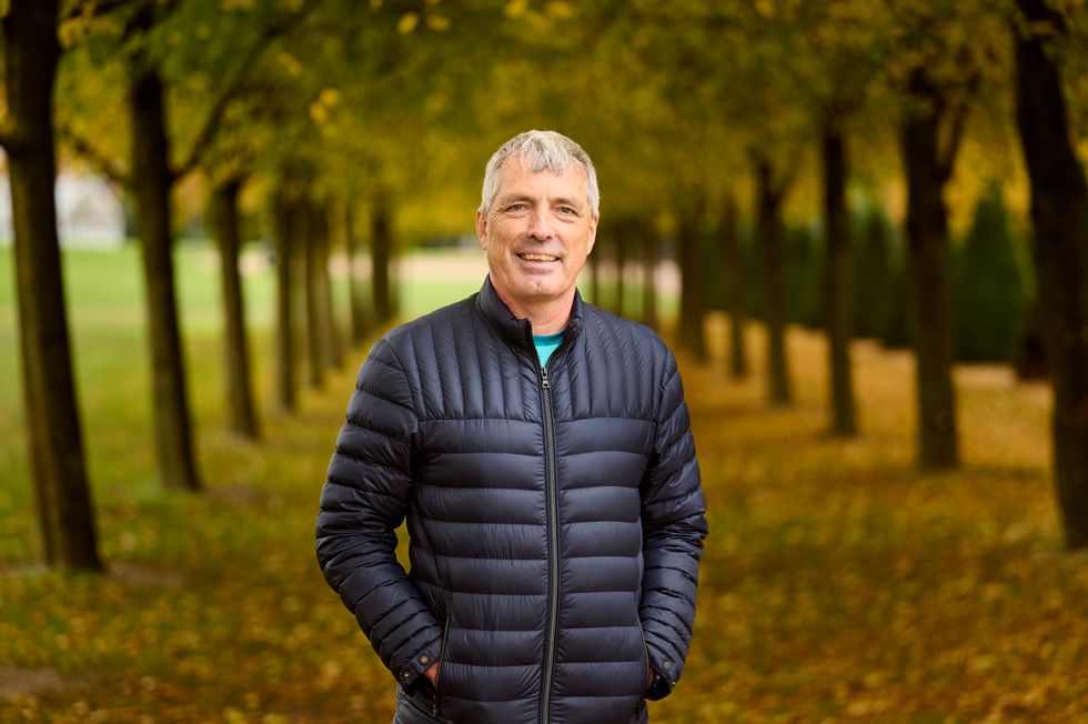 Stephen Lappin smiling, standing on a tree-lined path