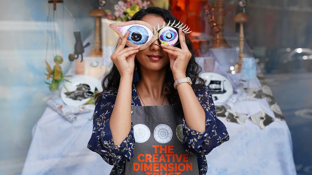 Student Roshni Patel holds two pieces of artwork in front of her eyes (Jonathan Brady/PA)