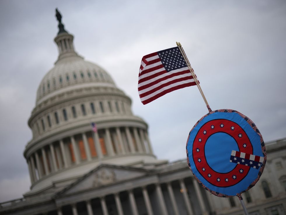 Supporters of Donald Trump fly a US flag with a symbol from the group QAnon as they gather outside the US Capitol on 6 January 2021 in Washington, DC
