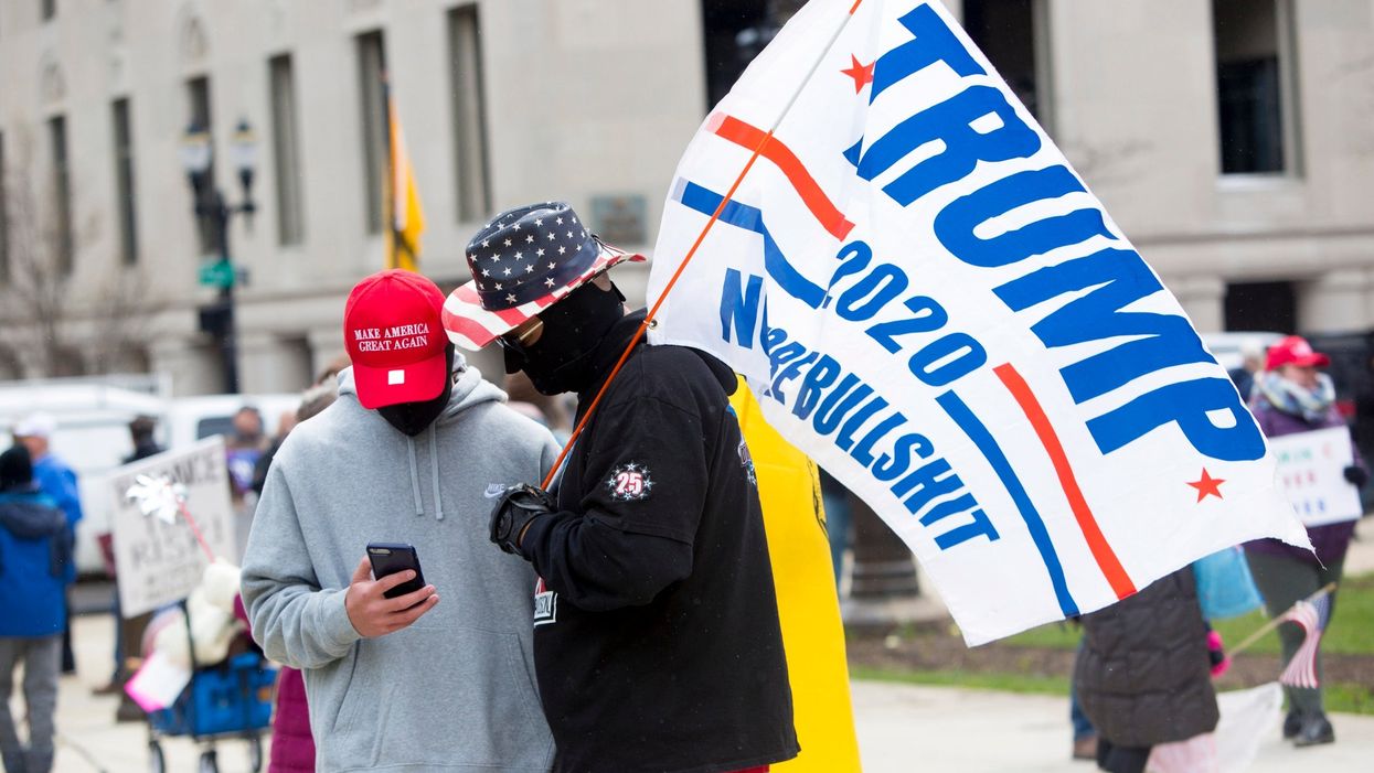 <p>Supporters wear MAGA hats and carry Trump flags at Michigan protest in 2020</p>